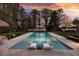 Evening shot of a luxury pool area, featuring sun shelves and an inviting view of the lake beyond at 320 Mary Jess Rd, Orlando, FL 32839