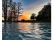 Tranquil pool view reflecting a vivid sunset with orange and pink hues, surrounded by trees at 320 Mary Jess Rd, Orlando, FL 32839