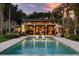 Twilight view of backyard pool with sun shelf and seating, patio, and lush tropical landscaping at 320 Mary Jess Rd, Orlando, FL 32839