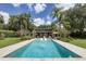 Backyard pool with a sun shelf, lounge chairs, lush landscaping, and a view of the house at 320 Mary Jess Rd, Orlando, FL 32839