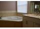 Bright bathroom features a garden tub, window with blinds, and a white vanity with granite counters at 369 James Cir, Lake Alfred, FL 33850