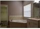 Bright bathroom features a garden tub, window with blinds, and a white vanity with granite counters at 369 James Cir, Lake Alfred, FL 33850