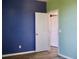 Bedroom featuring a bright navy blue wall, and a white door to another room, with wood look flooring at 369 James Cir, Lake Alfred, FL 33850