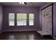 Bedroom with laminate wood flooring, three window view, stone fireplace on wall and purple paint at 369 James Cir, Lake Alfred, FL 33850