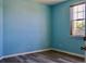 Bedroom showcasing an aqua wall, one window, and wood look flooring at 369 James Cir, Lake Alfred, FL 33850