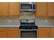 Modern kitchen with stainless steel appliances, light wood cabinetry, and granite countertops at 369 James Cir, Lake Alfred, FL 33850