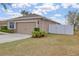 Exterior view showcasing the home's two-car garage, fenced yard, and well-maintained landscaping at 427 Highland Meadows St, Davenport, FL 33837