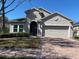Stucco home with attached garage and paver driveway and some landscaping at 457 Bridgeford Crossing Blvd, Davenport, FL 33837