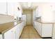 A galley kitchen features white cabinets, countertops, tile flooring, and appliances at 532 Madison Ave, Orlando, FL 32805
