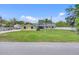 Charming yellow single-story home with a large grassy front yard, palm tree, and an American flag at 5800 Spruce Creek Woods Dr, Port Orange, FL 32127