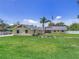Attractive single-story yellow home on a large lot with an American flag and green lawn at 5800 Spruce Creek Woods Dr, Port Orange, FL 32127