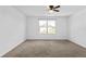 Bedroom featuring neutral carpet, white walls, ceiling fan, and a backyard view from the window at 597 Madison Dr, Davenport, FL 33837