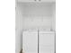 Efficient laundry closet with a side-by-side washer and dryer and a storage shelf above at 597 Madison Dr, Davenport, FL 33837