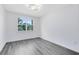 A bright bedroom with gray floors, a window and a modern light fixture at 6685 Queens Borough Ave # 202, Orlando, FL 32835