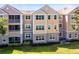 Rear exterior view of multi-story condominium building with patios and green spaces at 6685 Queens Borough Ave # 202, Orlando, FL 32835