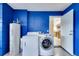 Bright laundry room with blue walls and appliances with doorway to kitchen at 8118 Fan Palm Way, Kissimmee, FL 34747