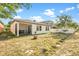 View of the backyard featuring a screen enclosed lanai, grassy area, and young landscaping at 9188 Chandler Dr, Groveland, FL 34736