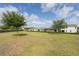 Expansive backyard featuring lush green grass, mature trees, and a view of the home's exterior at 9188 Chandler Dr, Groveland, FL 34736