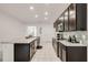 Spacious kitchen with dark cabinets, stainless steel appliances, a large island with a sink, and tiled flooring at 9188 Chandler Dr, Groveland, FL 34736