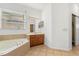 Bright bathroom with tile flooring, a soaking tub, vanity, mirror and ample lighting at 9469 Edenshire Cir, Orlando, FL 32836