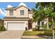 Two story home with a two car garage, manicured lawn and garden, and a red front door at 9469 Edenshire Cir, Orlando, FL 32836