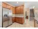 Kitchen featuring stainless steel refrigerator and wooden cabinets with adjacent stairwell at 9469 Edenshire Cir, Orlando, FL 32836