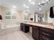 Bathroom featuring a tub, tiled floors, dual sinks with granite counters and dark wood cabinets at 1210 Pallister Ln, Lake Mary, FL 32746