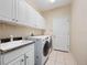 The laundry room offers ample storage with upper cabinets and modern front-load washer and dryer at 1210 Pallister Ln, Lake Mary, FL 32746