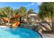 Community pool featuring a winding waterslide, waterfall features, and lush landscaping at 4582 Terrasonesta Dr, Davenport, FL 33837
