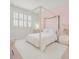 Charming bedroom with a four-poster bed, soft pink accents, and natural light from the window at 10254 Beechwood Ln, Orlando, FL 32832