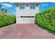 A two-car garage and private brick driveway are surrounded by lush, green hedges at 10254 Beechwood Ln, Orlando, FL 32832