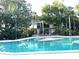 Community pool with a unique island feature surrounded by greenery and lounge chairs at 200 Maitland Ave # 87, Altamonte Springs, FL 32701