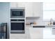 Stainless steel appliances, including a microwave and oven, are framed by custom white cabinets at 4012 Meandering Bay Dr, Apopka, FL 32712