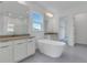 Bright bathroom featuring a soaking tub, double vanity, and a large mirror at 10013 Brocksport Cir, Gotha, FL 34734