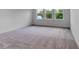 A well-lit bedroom featuring three large windows, white walls, and neutral carpeting at 10013 Brocksport Cir, Gotha, FL 34734