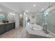 Luxurious bathroom featuring a soaking tub, glass-enclosed shower, dual vanity, and stylish tile and wallpaper design at 1062 Lakeside Estates Dr, Apopka, FL 32703