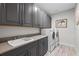 The laundry room features modern grey cabinets, solid surface countertops, and updated machines at 1062 Lakeside Estates Dr, Apopka, FL 32703