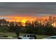 Beautiful sunset over the trees with a white Jeep in the driveway at 12067 Eastmoor Dr, Winter Garden, FL 34787