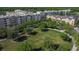 An aerial view showcasing community green space with mature trees and multi-story apartment buildings nearby at 12955 Cats Claw Ln, Orlando, FL 32828