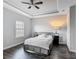 A clean bedroom featuring a tray ceiling, plush bedding, dark wood floors, and shuttered windows at 12955 Cats Claw Ln, Orlando, FL 32828