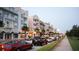 A view down a street lined with colorful buildings, sidewalks, parked cars, and palm trees at 12955 Cats Claw Ln, Orlando, FL 32828
