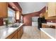Functional kitchen featuring stainless steel sink, wood cabinets, and a view into the laundry area at 13416 Greenpointe Dr, Orlando, FL 32824