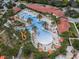 Resort-style pool featuring a water slide, palm trees, ample seating, and a clubhouse with a terracotta tiled roof at 1415 Oak Marsh St, Davenport, FL 33837