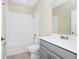 A full bathroom with a tub, white tile surround, and a vanity with a sink and a gray cabinet at 1415 Oak Marsh St, Davenport, FL 33837