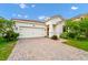 Charming home with a brick driveway, manicured landscaping, and a two-car garage at 1415 Oak Marsh St, Davenport, FL 33837