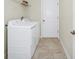 Functional laundry room with washer, dryer, tile floor and overhead shelving, perfect for efficient home management at 1415 Oak Marsh St, Davenport, FL 33837
