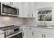 Kitchen showcasing stainless steel appliances, granite countertops, a white backsplash, and white cabinets at 1475 James St, New Smyrna Beach, FL 32168