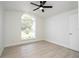 Bright bedroom features a ceiling fan, large arched window, and light hardwood flooring at 2218 Newt St, Orlando, FL 32837