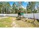 A backyard with a playset and swingset with a view of tall trees and a white fence at 236 Elm Ct, Kissimmee, FL 34759