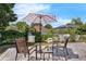 Patio furniture with two chairs, a small table, and a striped umbrella with plants as decoration at 248 Wallrock Ct, Ocoee, FL 34761